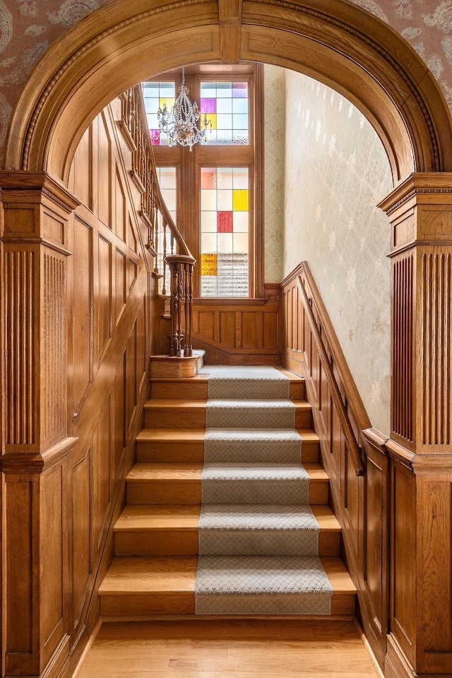 stairs featuring hardwood / wood-style flooring and a chandelier