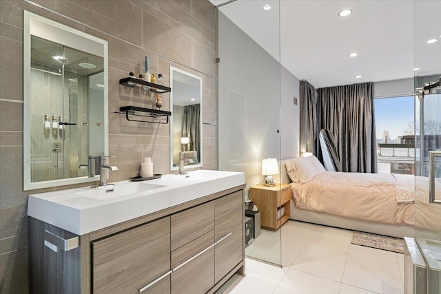 bathroom featuring double vanity, tile patterned floors, an enclosed shower, tile walls, and a sink