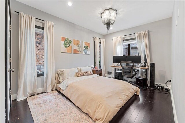 bedroom featuring dark wood finished floors, an inviting chandelier, and baseboards