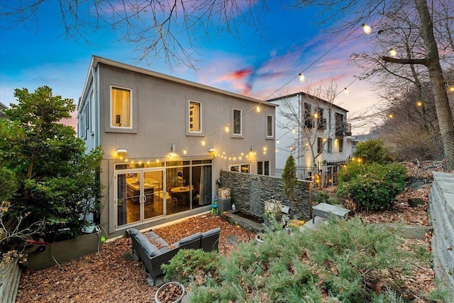 back of property at dusk featuring stucco siding