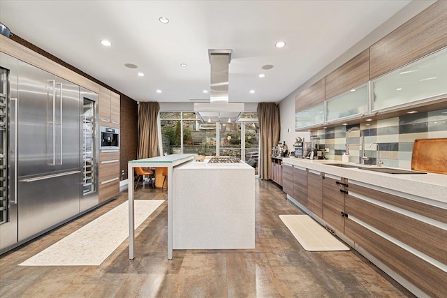 kitchen with tasteful backsplash, glass insert cabinets, light countertops, island exhaust hood, and modern cabinets