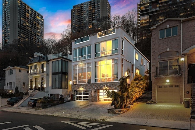 exterior space featuring decorative driveway, an attached garage, and stucco siding