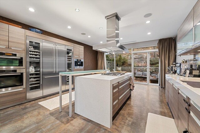 kitchen featuring island exhaust hood, stainless steel appliances, light countertops, modern cabinets, and a center island