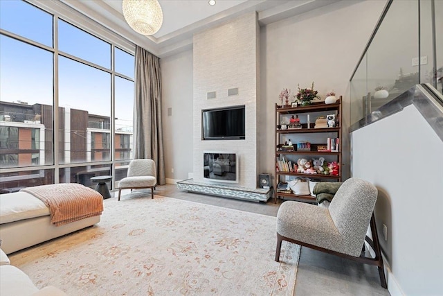 living room with baseboards, a large fireplace, a high ceiling, and wood finished floors