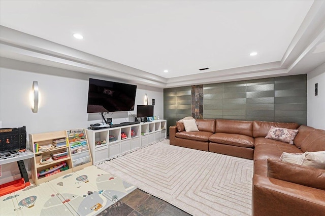 living room with recessed lighting, visible vents, a raised ceiling, and an accent wall