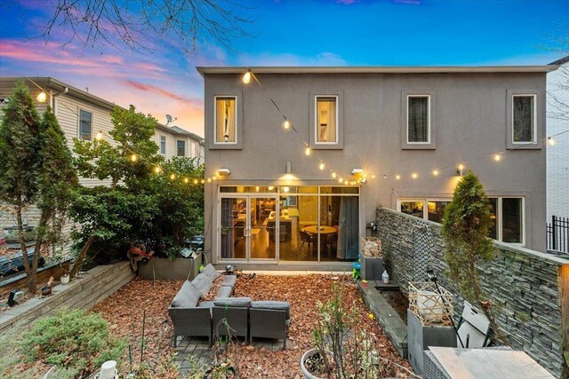 back of house at dusk with stucco siding and fence