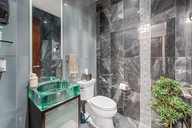 bathroom featuring vanity, tile walls, and toilet