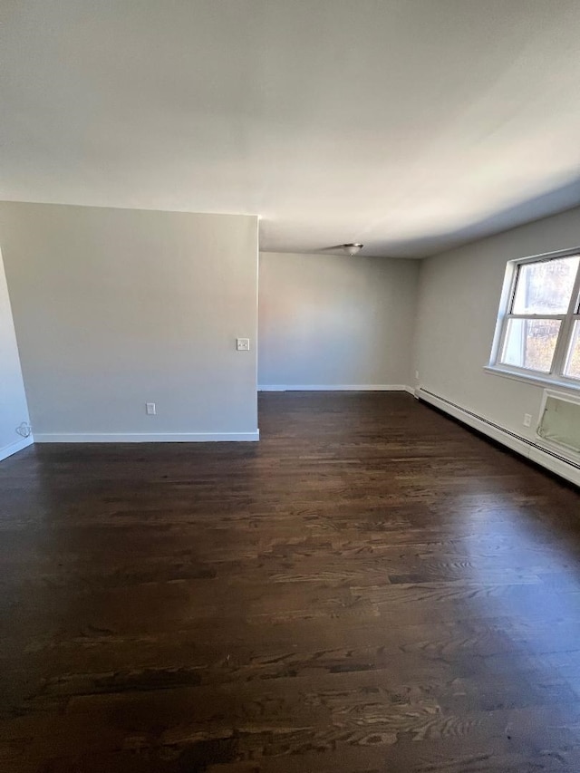 spare room with a baseboard radiator and dark hardwood / wood-style flooring