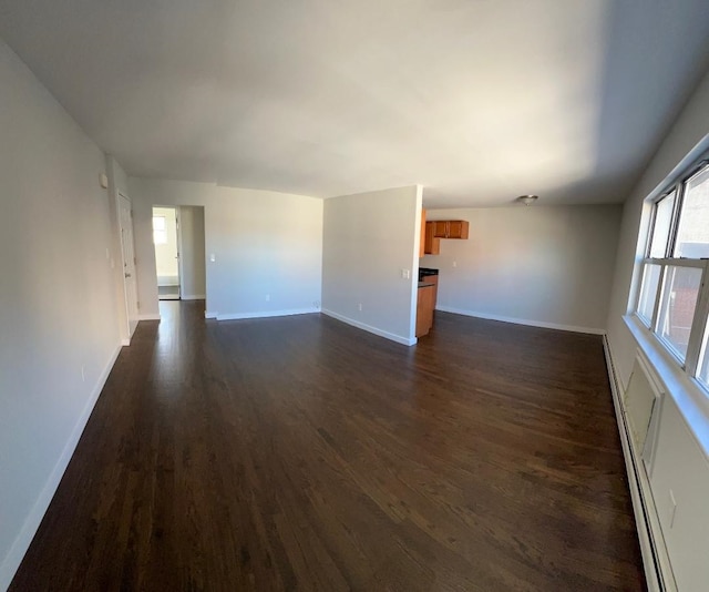 unfurnished room with dark hardwood / wood-style floors and a baseboard heating unit