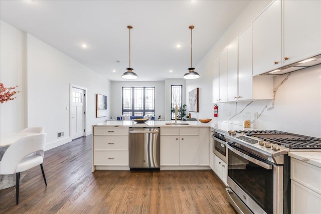 kitchen with stainless steel appliances, decorative light fixtures, decorative backsplash, and kitchen peninsula