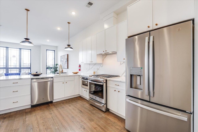 kitchen featuring sink, white cabinetry, tasteful backsplash, pendant lighting, and appliances with stainless steel finishes