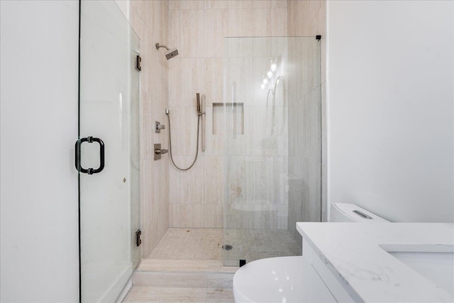 bathroom featuring toilet, vanity, and a shower with shower door