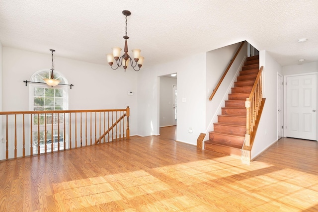 unfurnished room featuring hardwood / wood-style floors, a textured ceiling, and an inviting chandelier