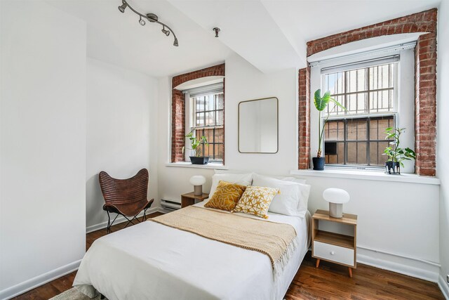347 Varick St Unit 114A, Jersey City, NJ 07302 - bedroom featuring a baseboard radiator, baseboards, wood finished floors, and rail lighting
