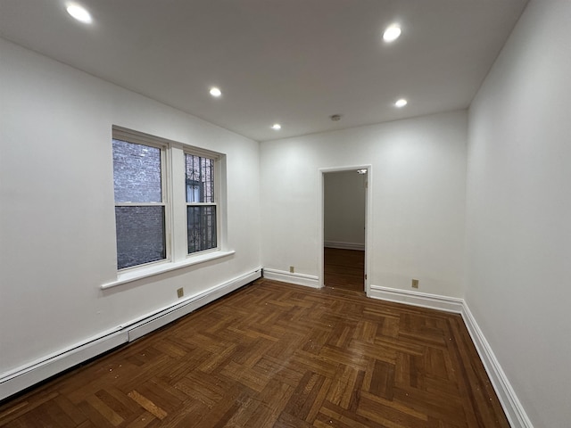 spare room featuring dark parquet flooring and a baseboard heating unit