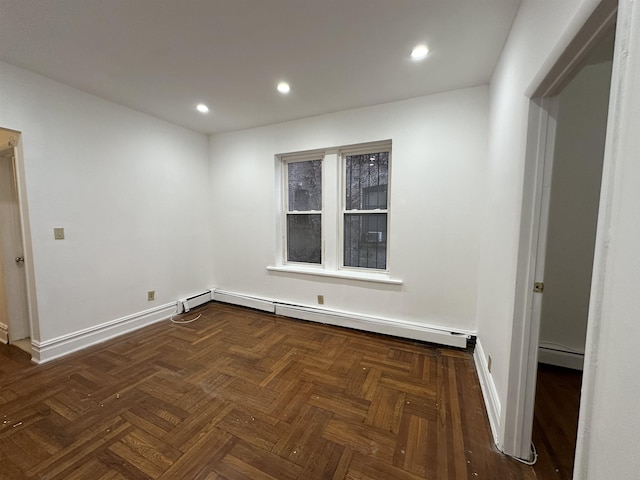 spare room featuring dark parquet flooring and a baseboard radiator