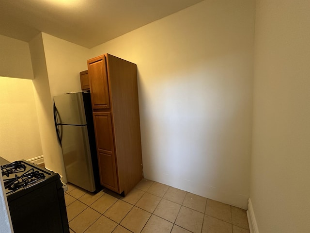 kitchen with stainless steel refrigerator, black range with gas cooktop, and light tile patterned flooring