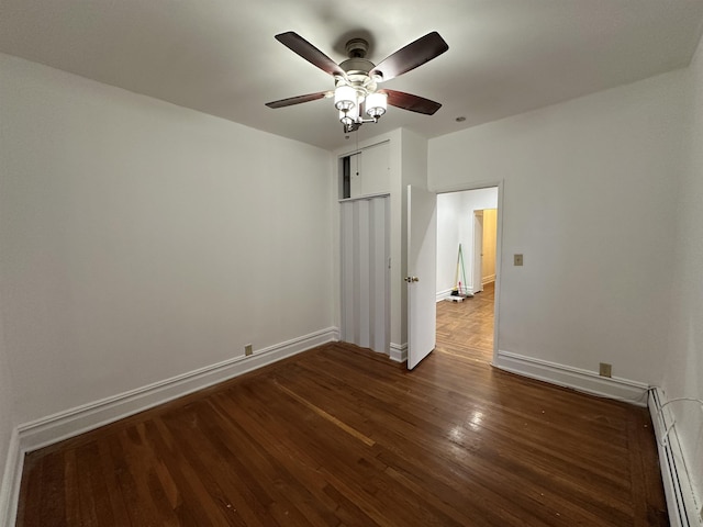 unfurnished bedroom featuring dark wood-type flooring, ceiling fan, and a baseboard heating unit