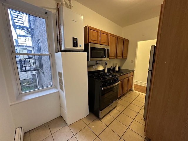 kitchen featuring water heater, sink, light tile patterned floors, and stainless steel appliances