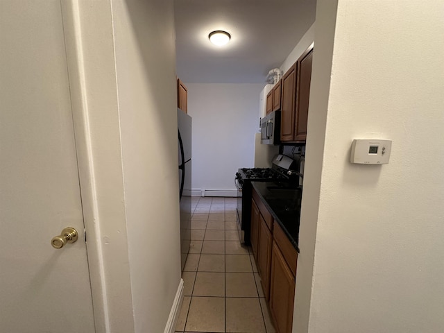 kitchen featuring refrigerator, black stove, light tile patterned floors, and baseboard heating