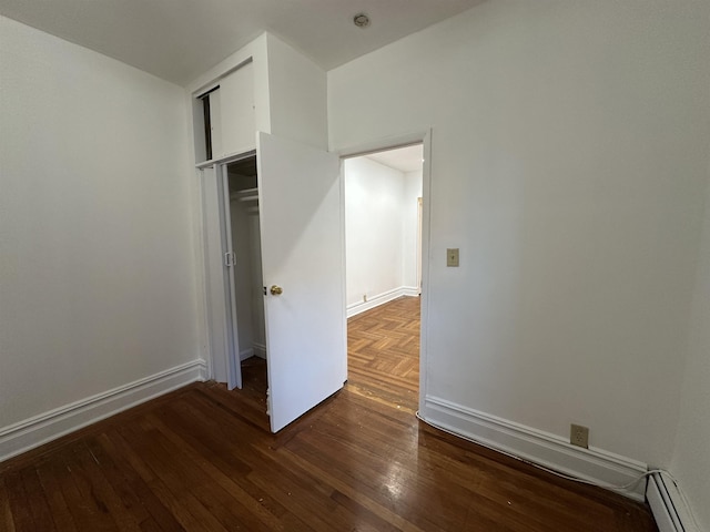 unfurnished bedroom with dark hardwood / wood-style floors, a closet, and a baseboard radiator