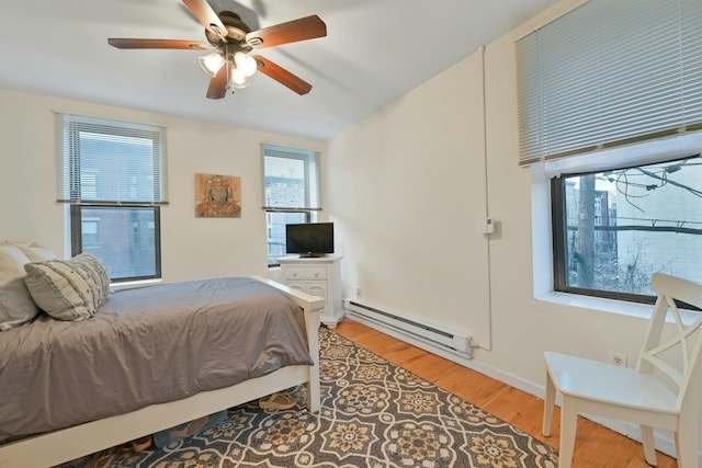 bedroom with hardwood / wood-style floors, a baseboard heating unit, and ceiling fan