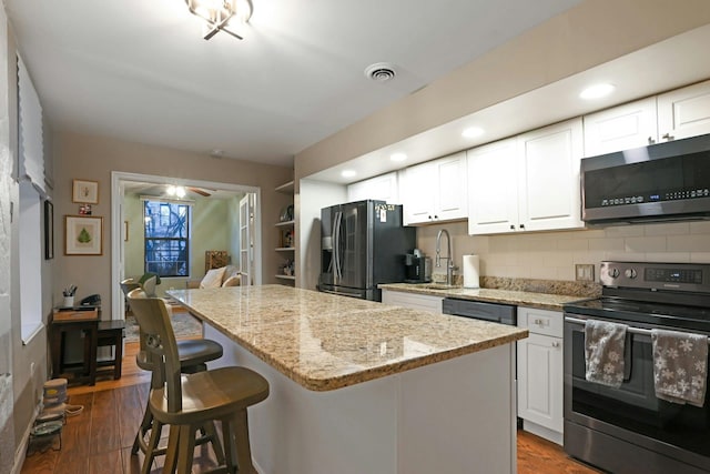 kitchen featuring sink, a center island, black appliances, and white cabinetry