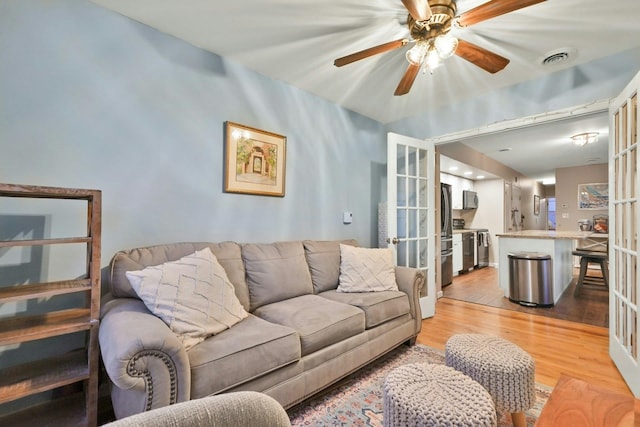 living room featuring ceiling fan, french doors, and light hardwood / wood-style floors