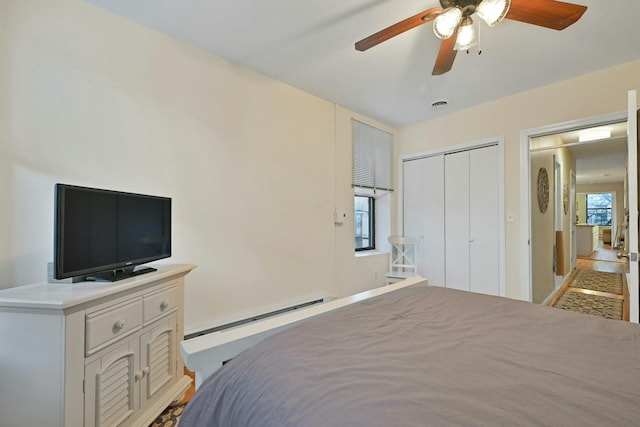 bedroom with ceiling fan, multiple windows, a closet, and a baseboard radiator