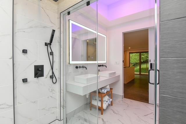 203 Stanhope Rd, Sparta, NJ 07871 - full bathroom with a marble finish shower, double vanity, and marble look tiles