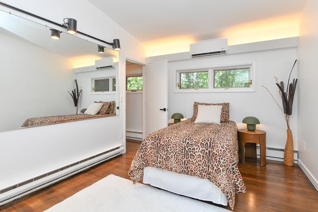 203 Stanhope Rd, Sparta, NJ 07871 - bedroom with a wall unit AC, baseboard heating, wood finished floors, and a baseboard radiator