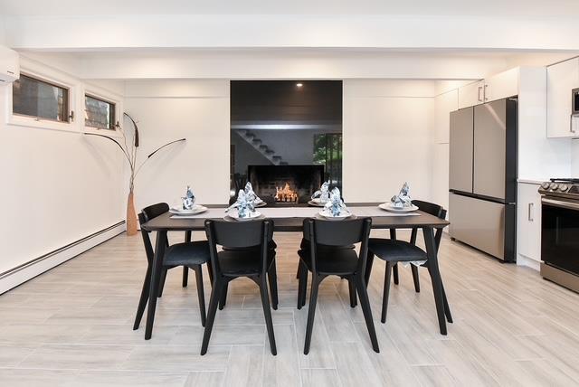 203 Stanhope Rd, Sparta, NJ 07871 - dining space with a lit fireplace, light wood-style floors, baseboard heating, and a wall mounted AC