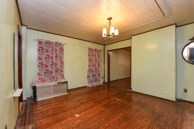 unfurnished room with radiator heating unit, dark hardwood / wood-style floors, and an inviting chandelier