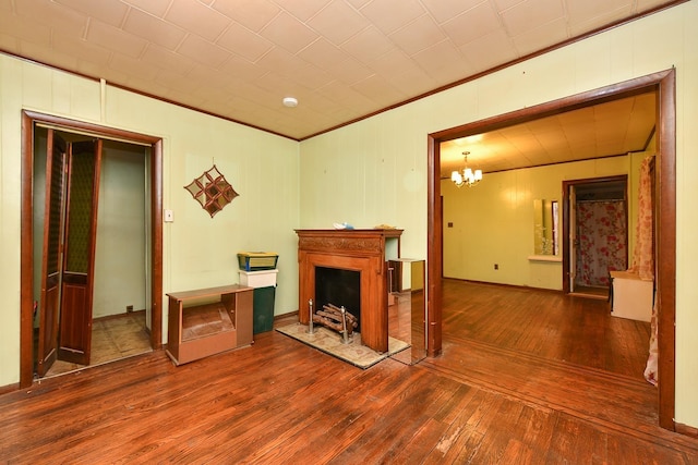 unfurnished living room featuring hardwood / wood-style flooring, a notable chandelier, and crown molding