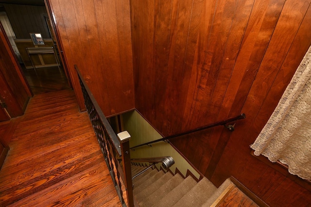 staircase featuring wood-type flooring and wooden walls