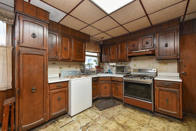 kitchen featuring washer / dryer, stove, tasteful backsplash, and a drop ceiling