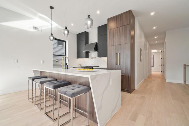 kitchen with hanging light fixtures, sink, light wood-type flooring, and a spacious island