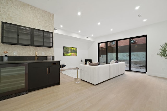 living room featuring wine cooler, wet bar, and light wood-type flooring