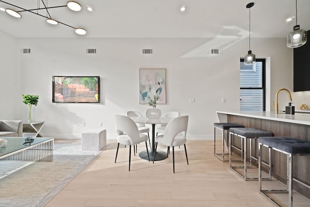 dining area with sink and light hardwood / wood-style floors