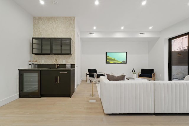 living room with wine cooler, wet bar, and light hardwood / wood-style flooring