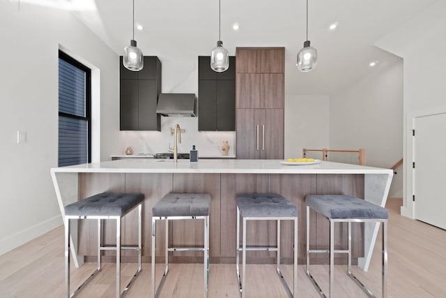 kitchen with light hardwood / wood-style flooring, pendant lighting, a kitchen bar, and a spacious island