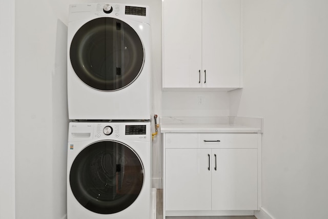 washroom featuring stacked washer and dryer and cabinets