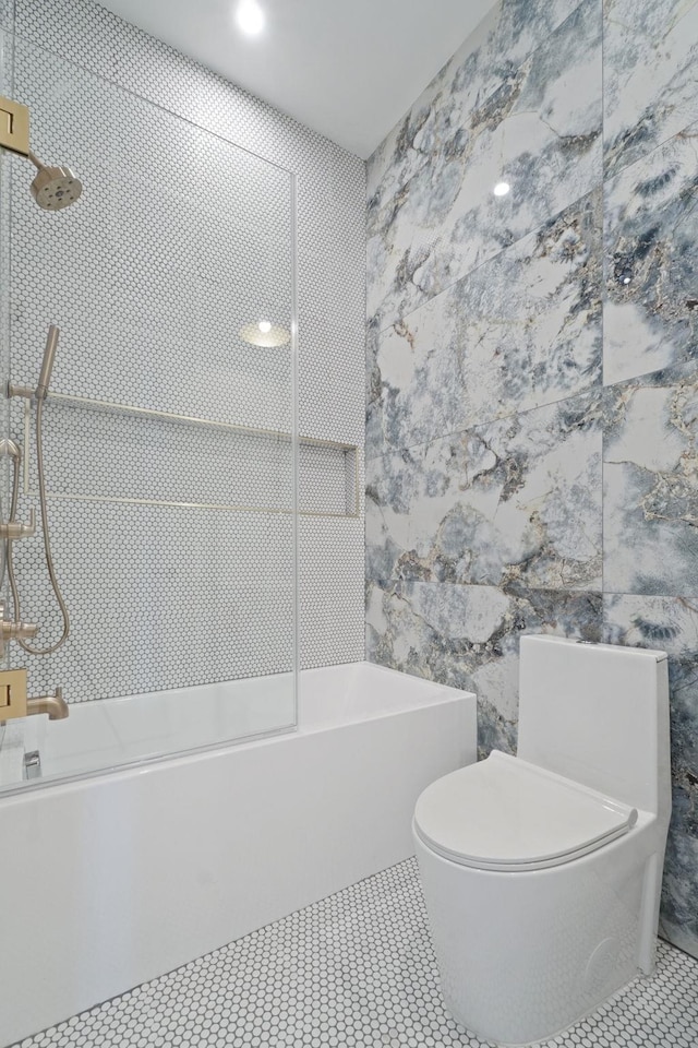 bathroom with tile walls, tiled shower / bath combo, tile patterned floors, and toilet