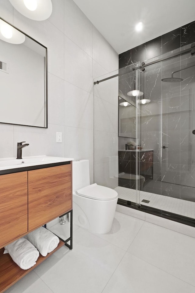 bathroom featuring a shower with door, tile walls, tile patterned flooring, vanity, and toilet