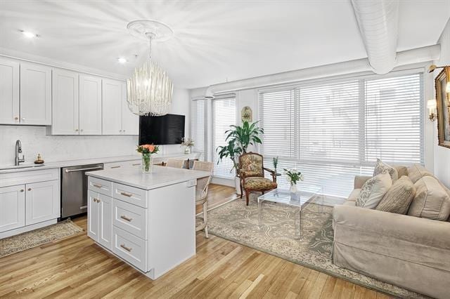 414 1st St Unit 1, Jersey City, NJ 07302 - kitchen with dishwasher, a chandelier, a breakfast bar area, light countertops, and white cabinetry