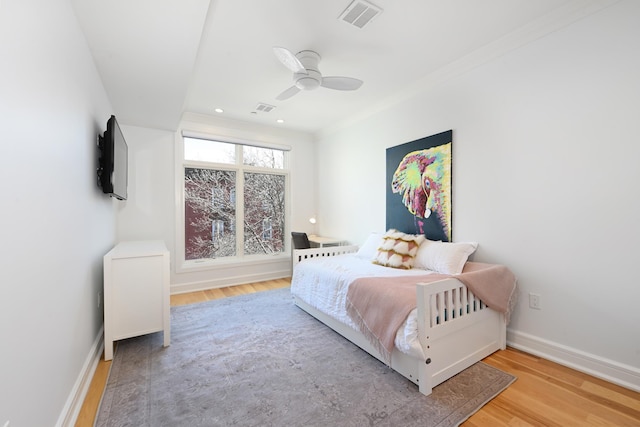 bedroom featuring ceiling fan, visible vents, baseboards, and wood finished floors