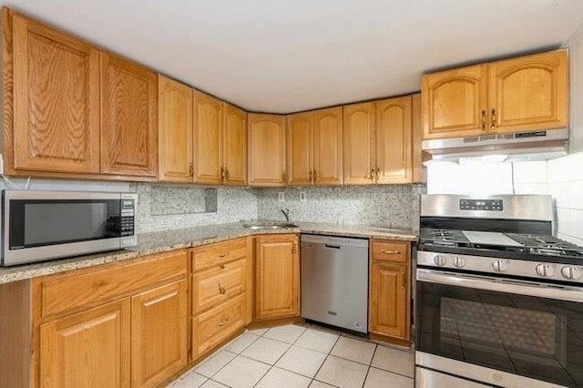 kitchen with a sink, decorative backsplash, stainless steel appliances, and under cabinet range hood