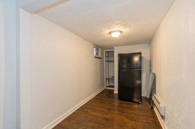 corridor featuring baseboards, a baseboard radiator, dark wood finished floors, and a textured ceiling