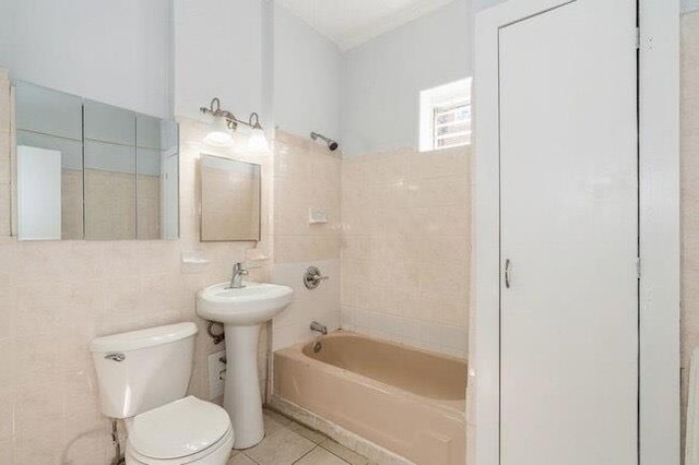 bathroom with a sink, tile patterned flooring, toilet, tile walls, and shower / bathing tub combination