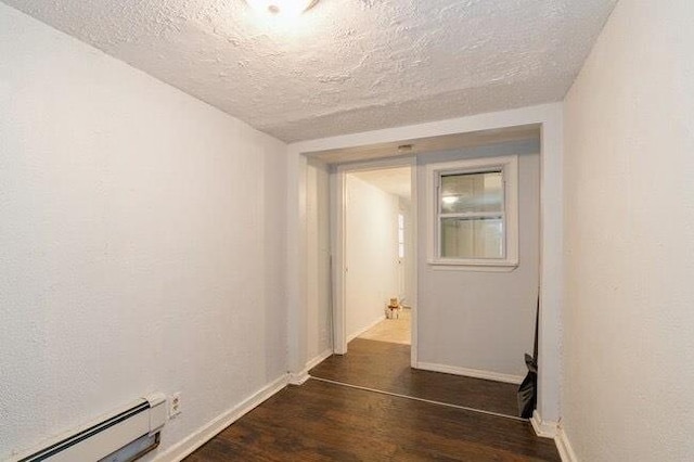hall featuring dark wood-type flooring, a baseboard radiator, baseboards, and a textured ceiling